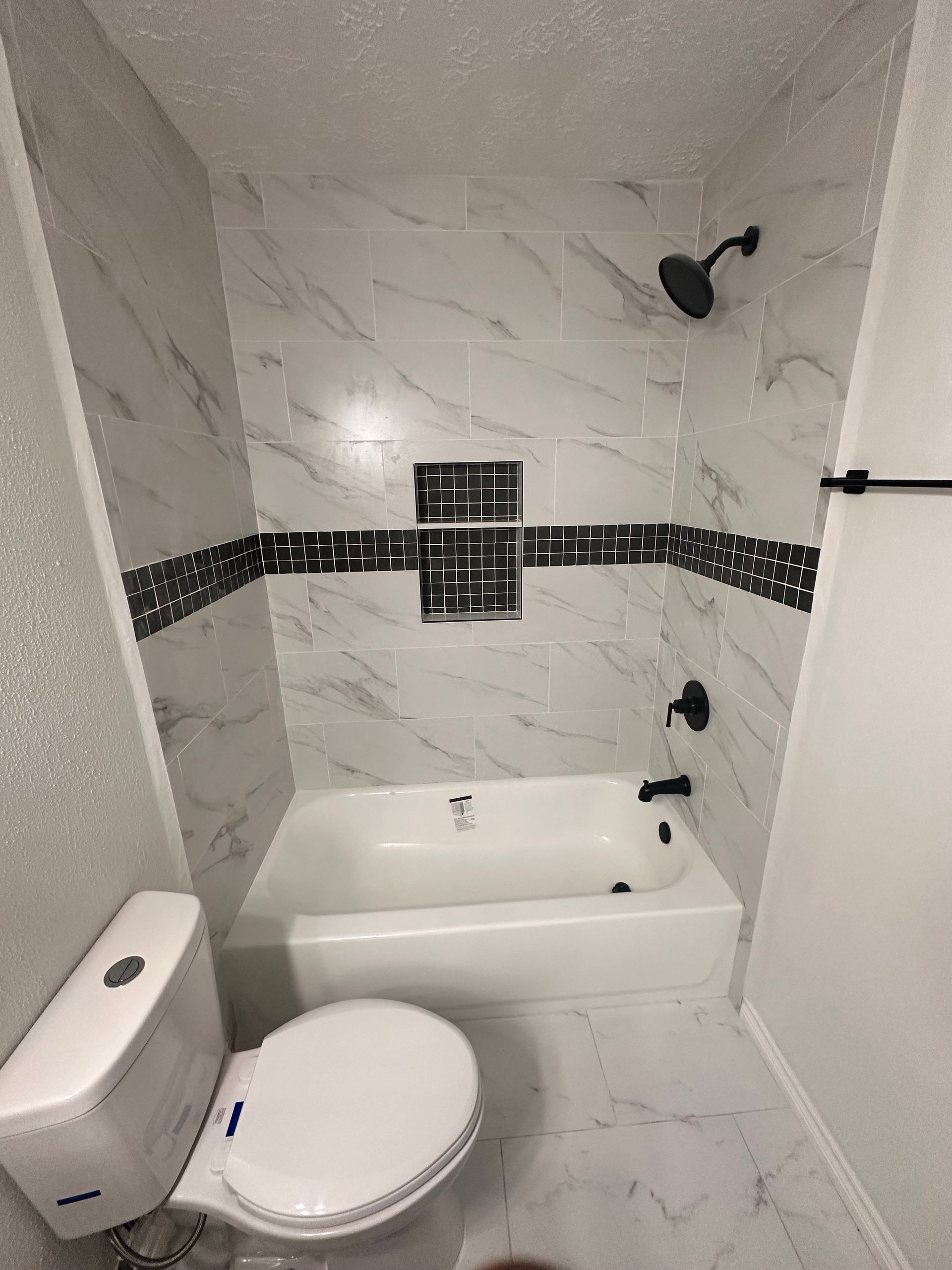 A bathroom with a toilet , bathtub and shower.