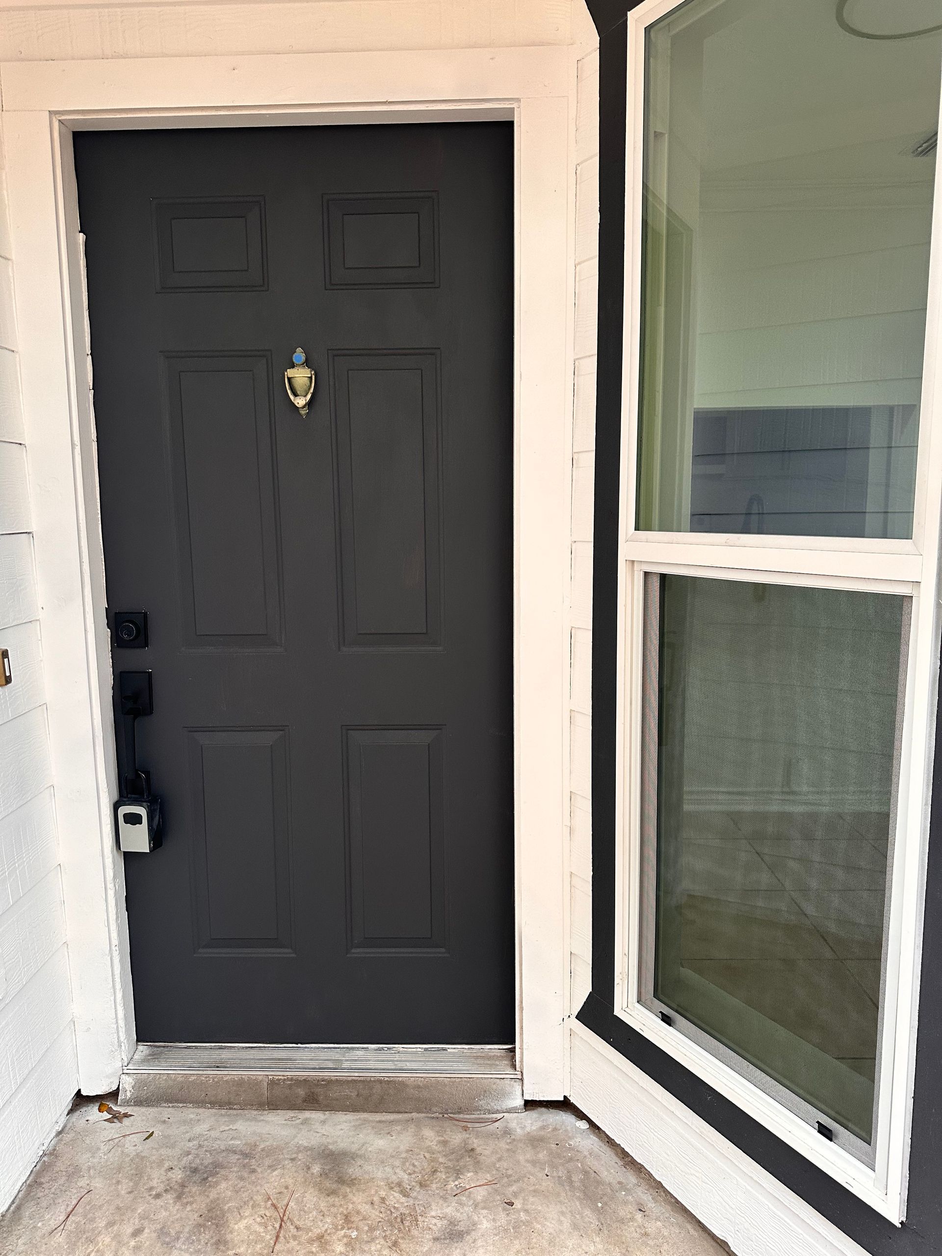 A black front door with a window on the side of a house.