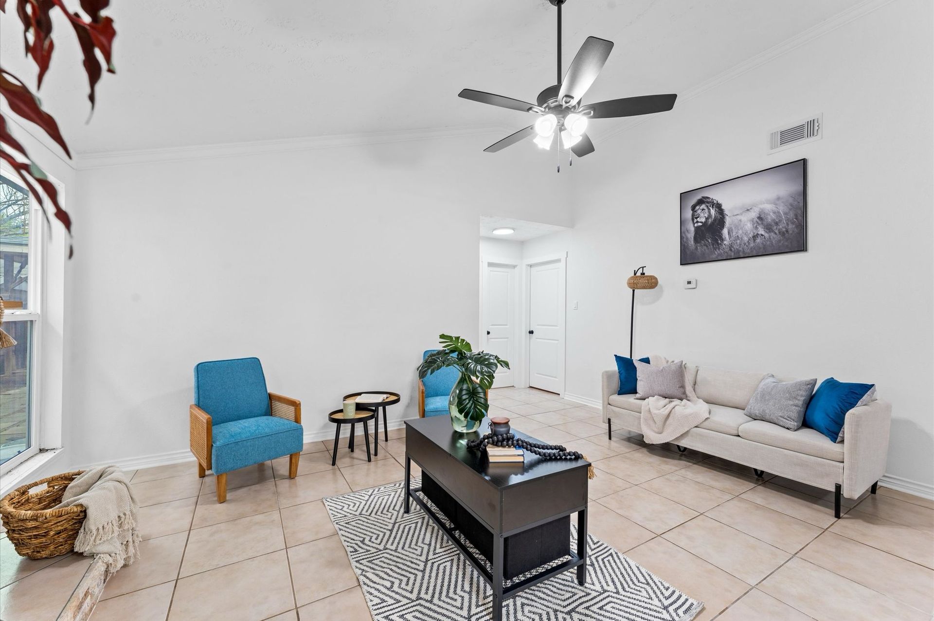 A living room with a couch , chairs , coffee table and ceiling fan.