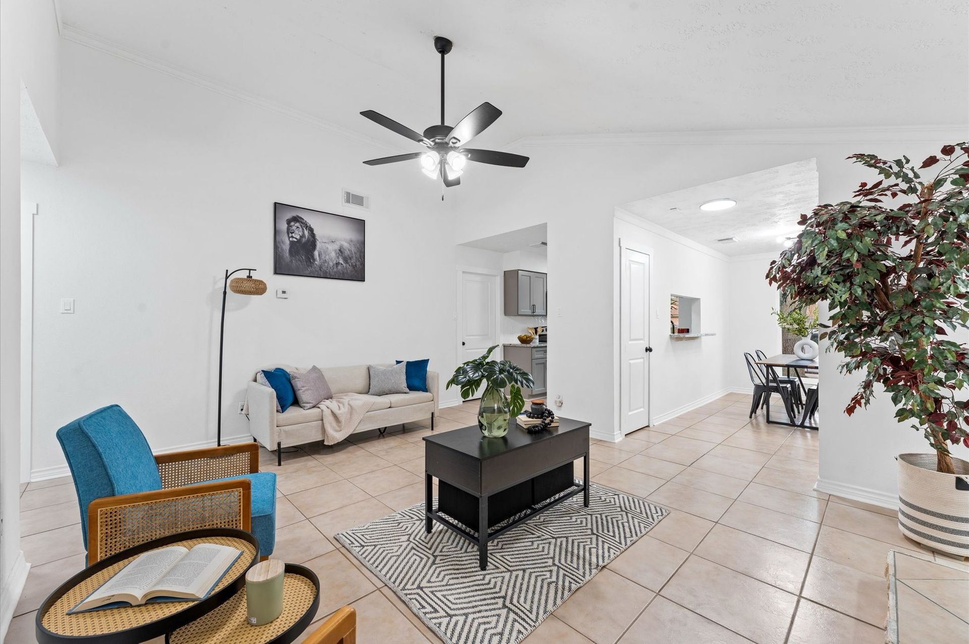 A living room with a couch , chair , coffee table and ceiling fan.