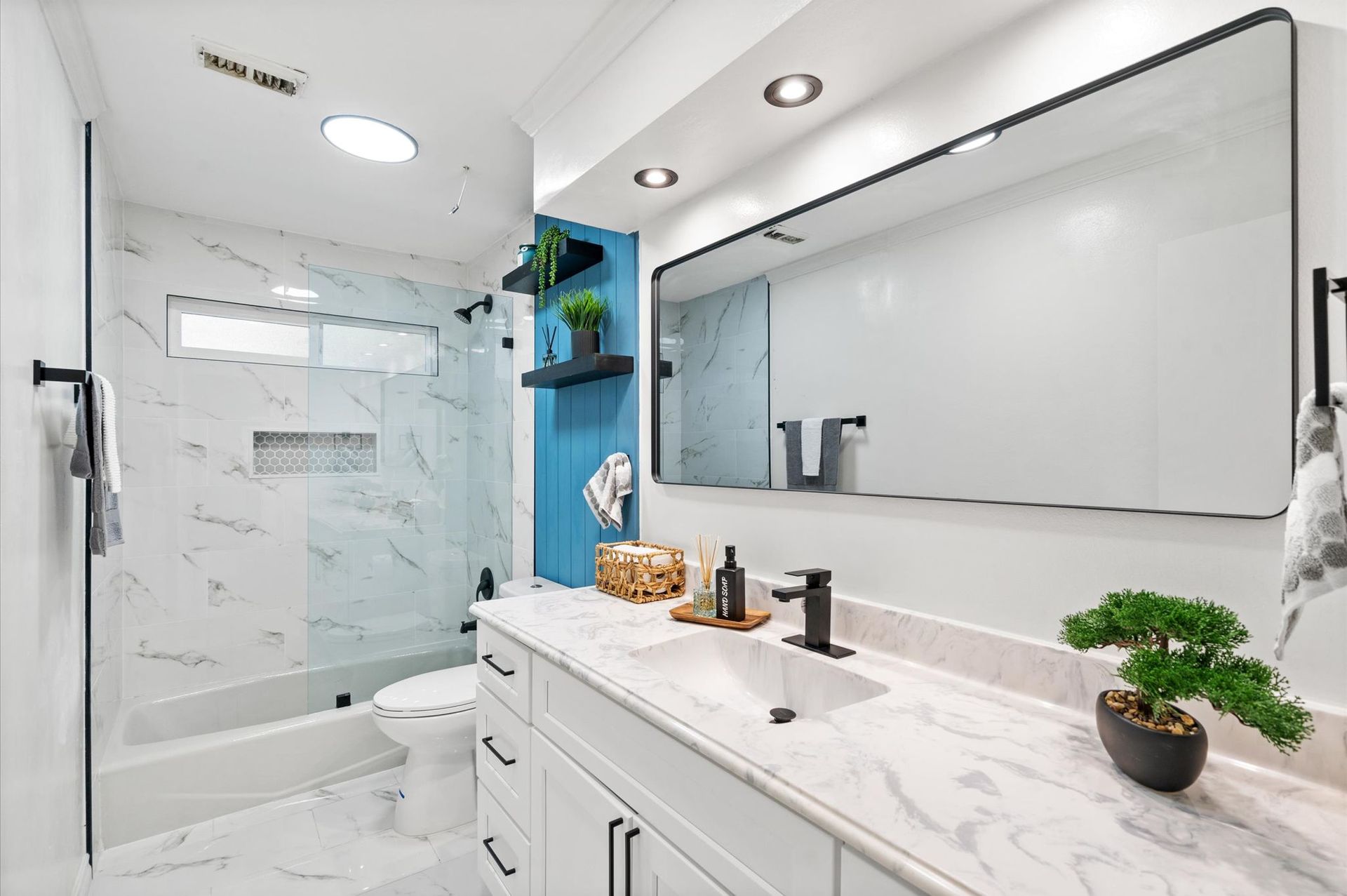 A bathroom with a sink , toilet , shower and mirror.