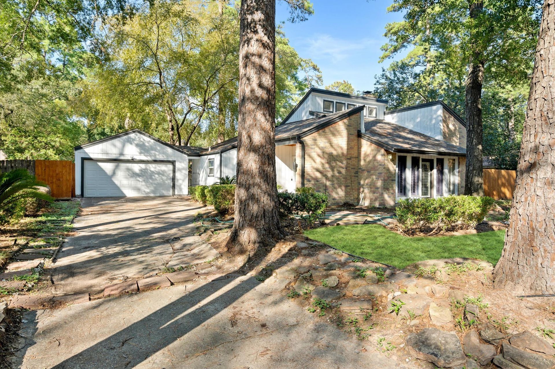 A house with a garage and a driveway is surrounded by trees.