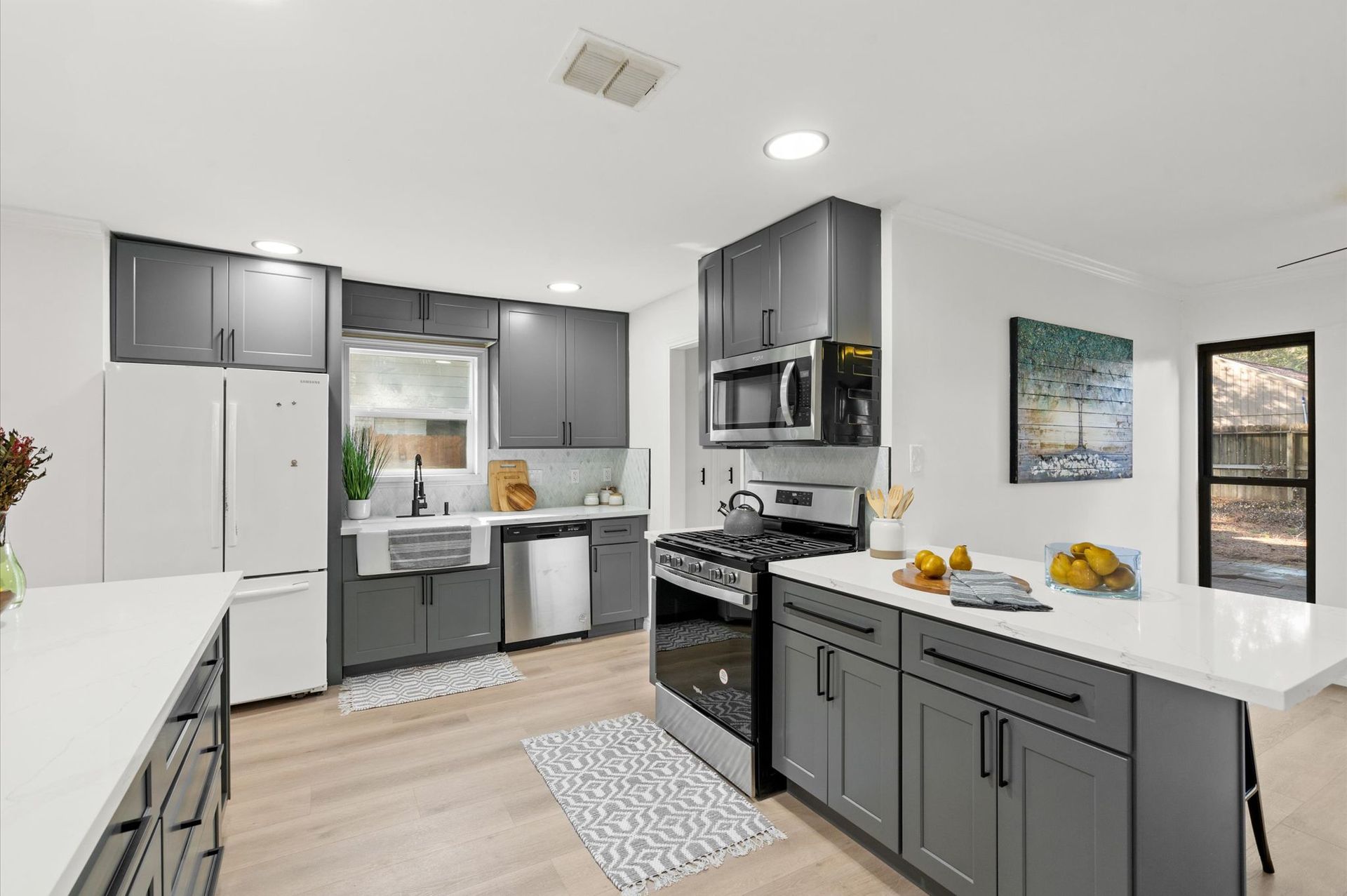 Modern kitchen with gray cabinets, stainless steel appliances, and a white island.