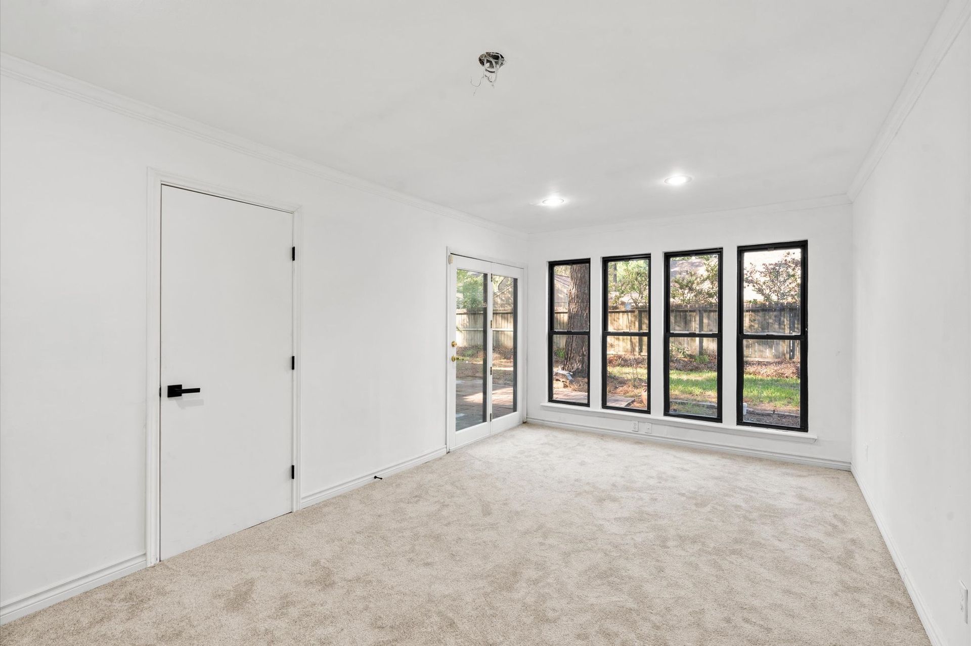 An empty room with a lot of windows and a carpeted floor.