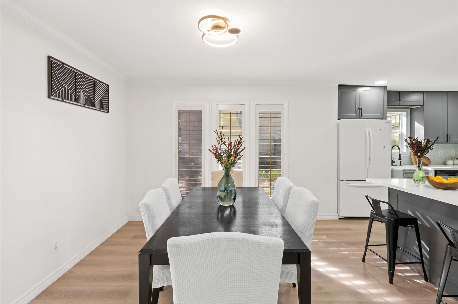 A dining room with a long table and chairs and a vase of flowers on it.