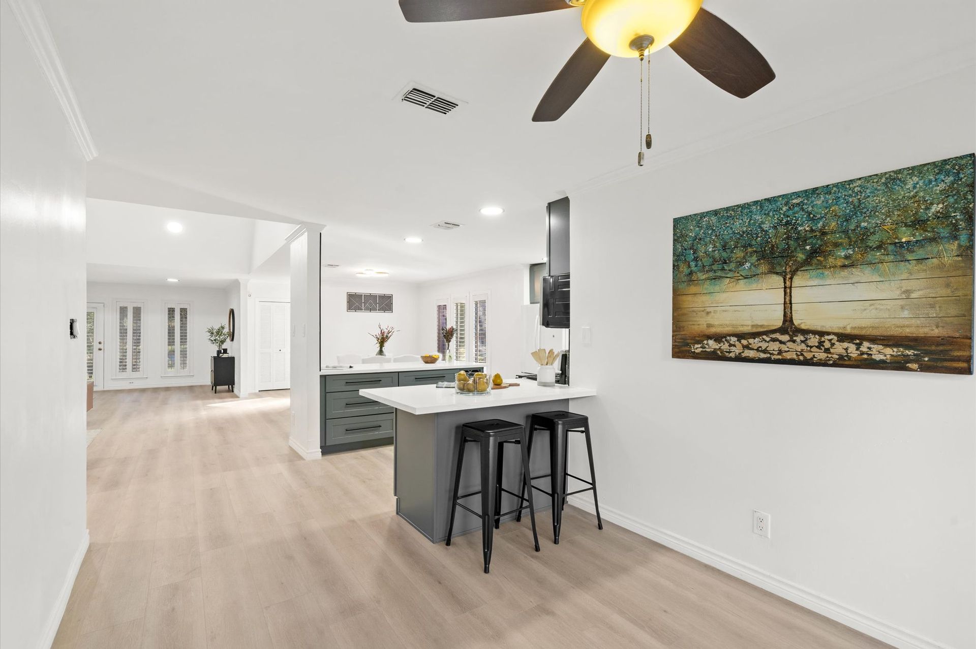 A kitchen with a ceiling fan and a painting on the wall.