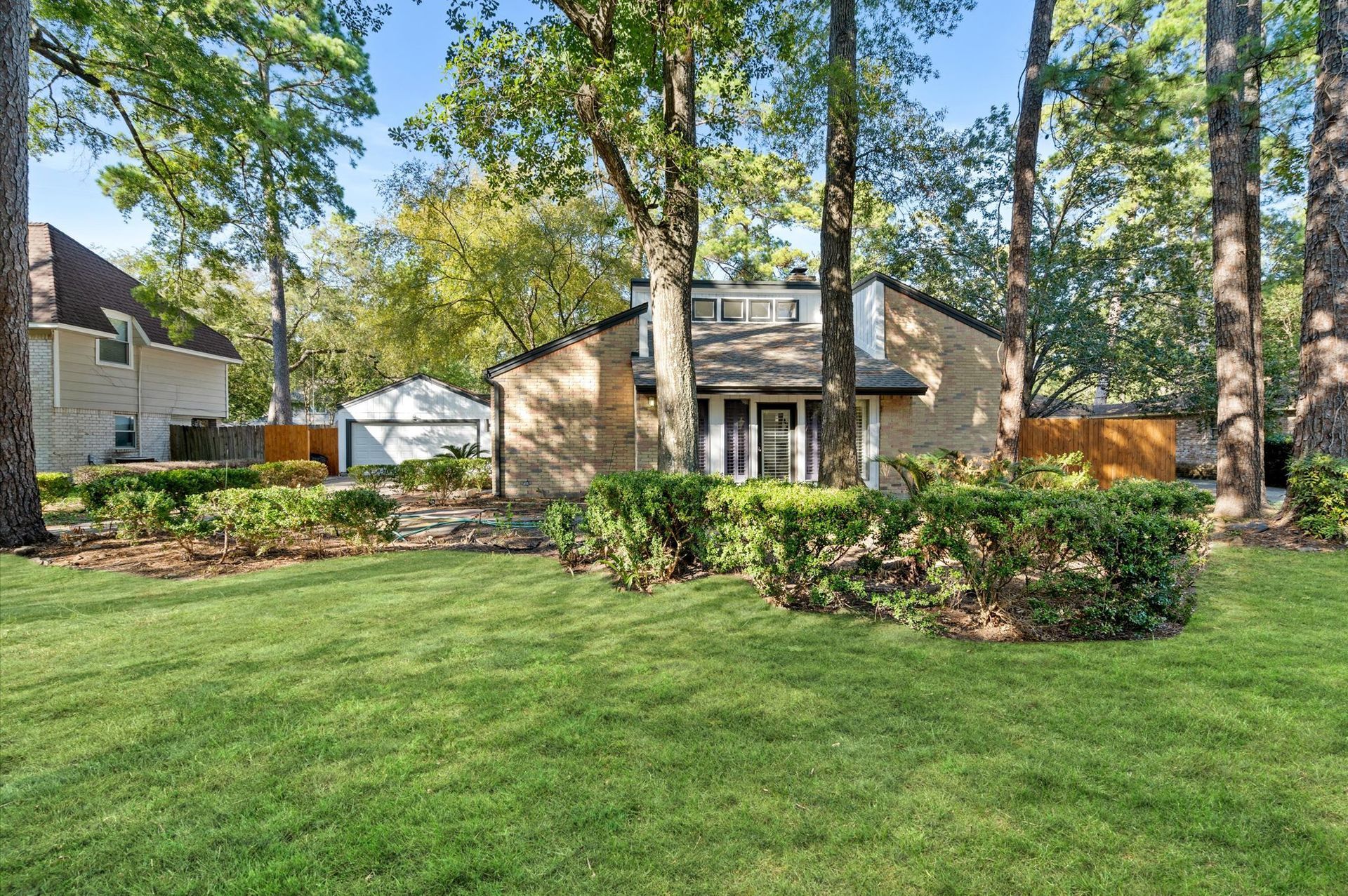 A house with a large lawn in front of it surrounded by trees.