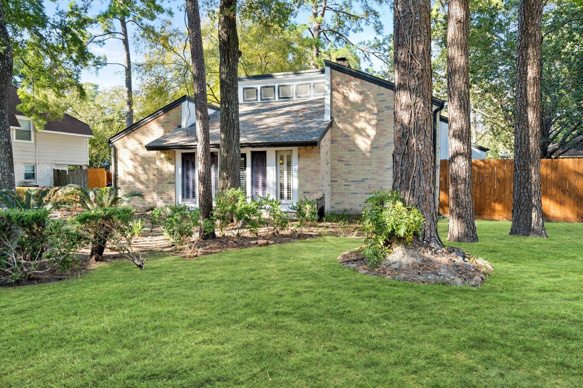 A house with a large lawn in front of it surrounded by trees.