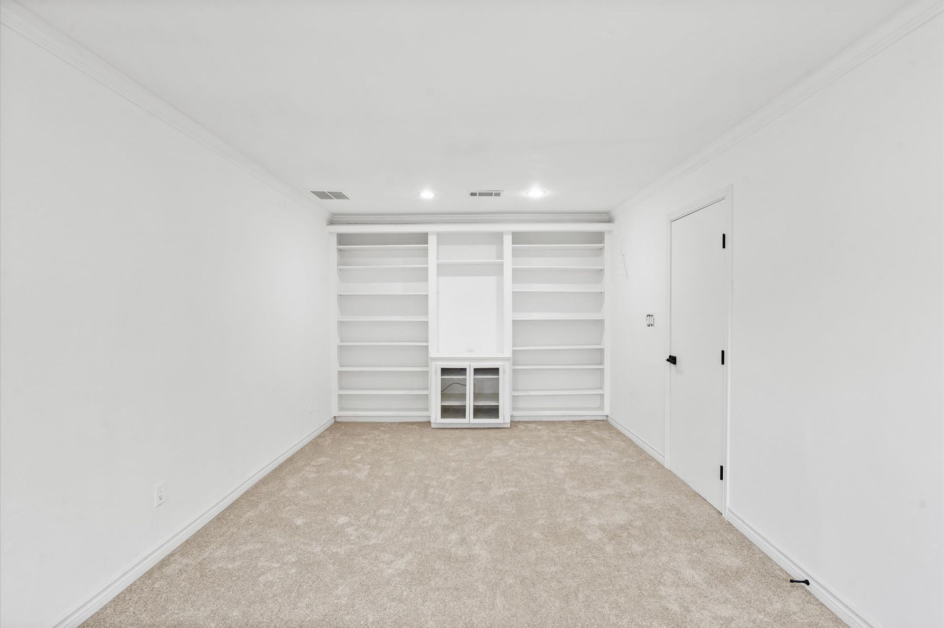 An empty room with a lot of shelves and a door.