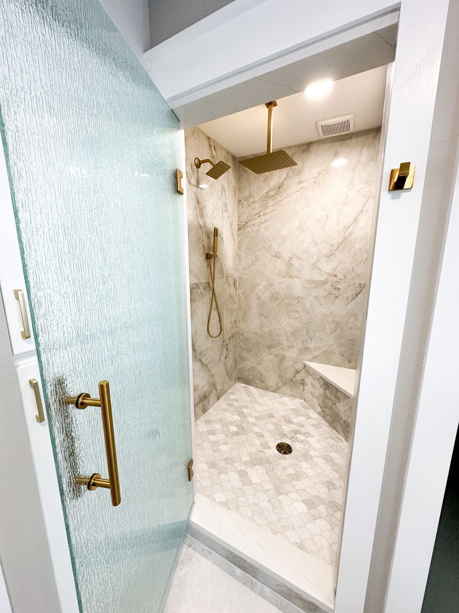 A bathroom with a walk in shower with a glass door.