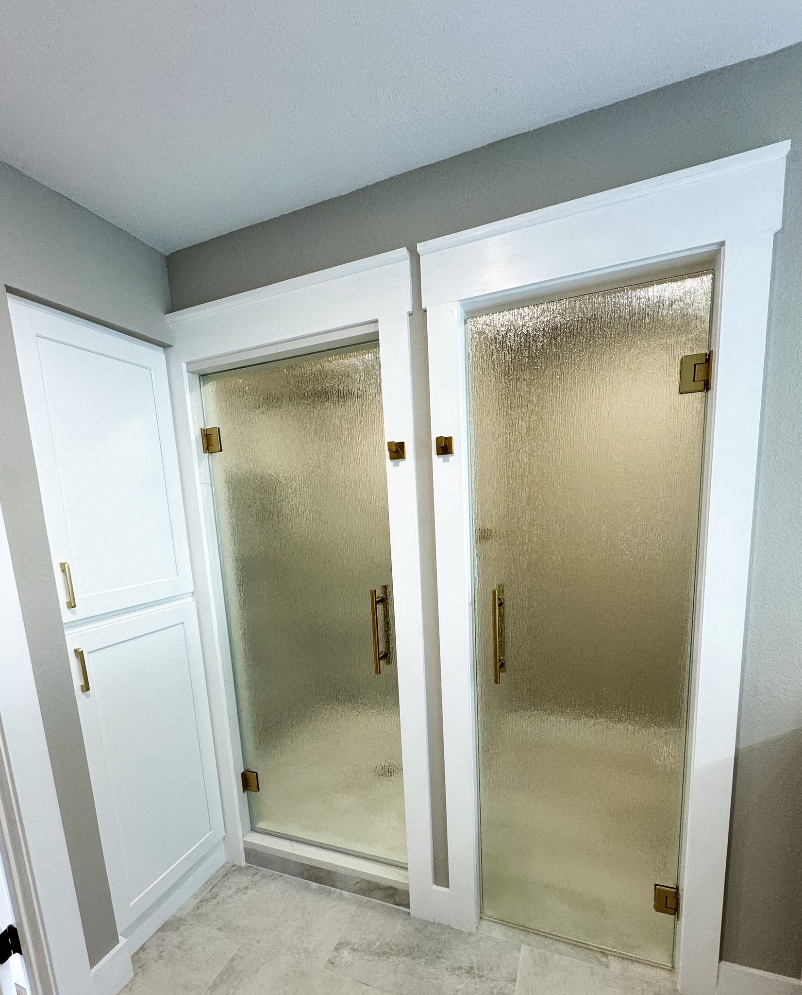 A bathroom with two glass shower doors and a white cabinet.