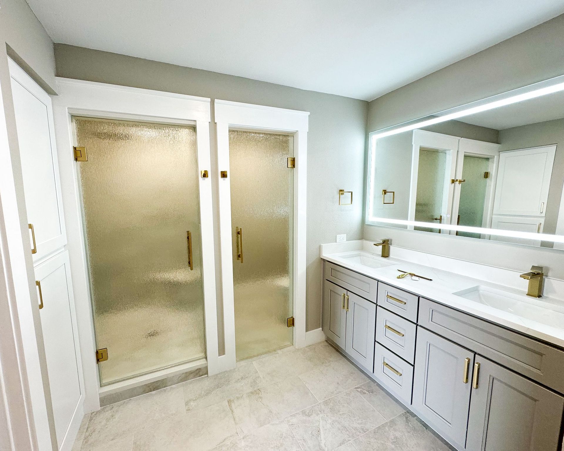 A renovated bathroom with two sinks , a shower , and a large mirror.