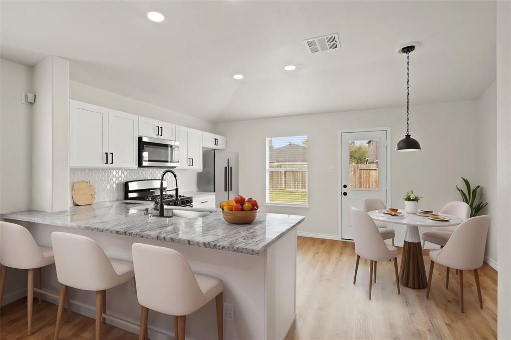 Bright, modern kitchen with white cabinets, granite countertops, and a dining area.