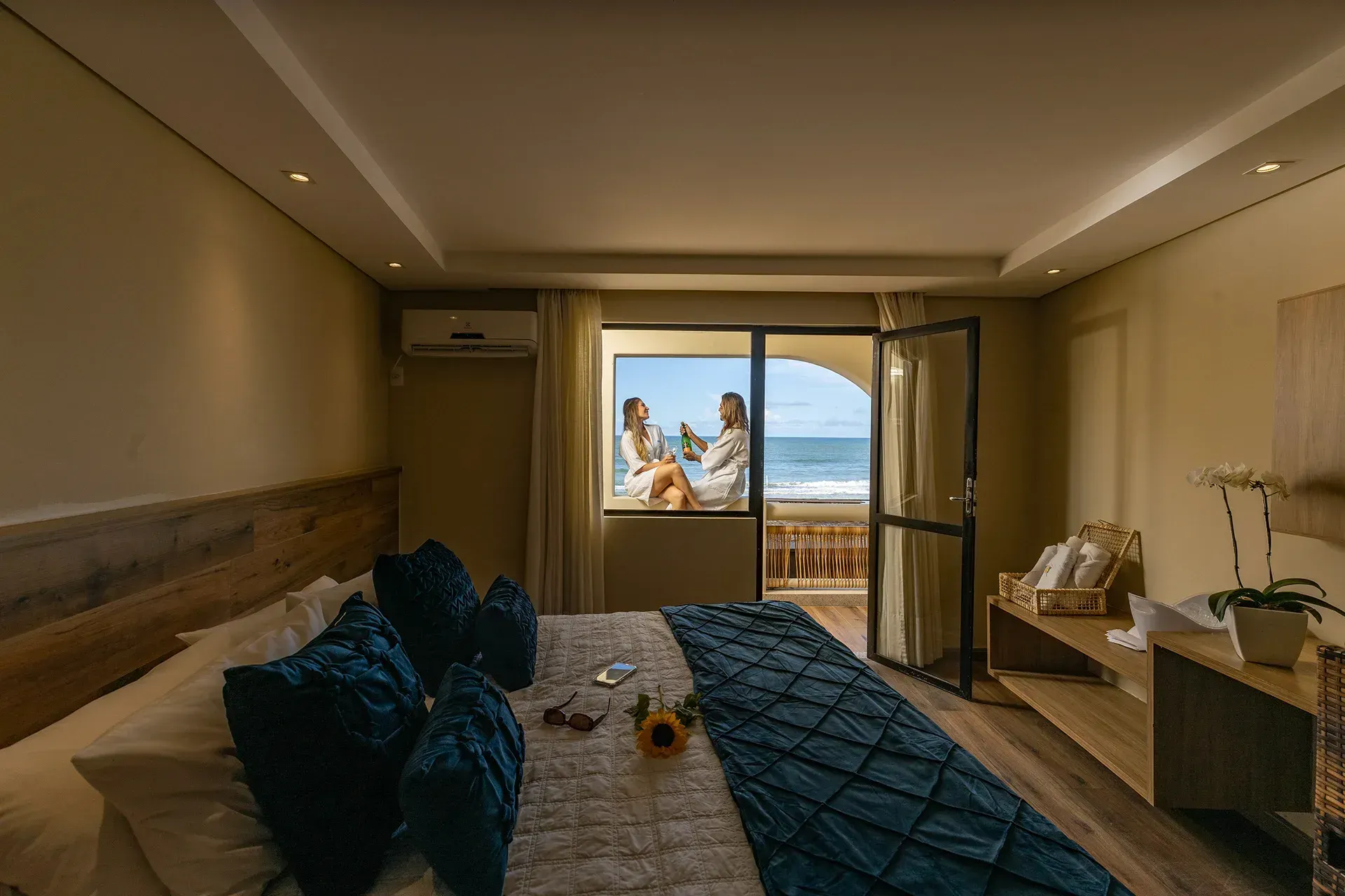 Um quarto de hotel com uma cama grande e varanda com vista para o mar.