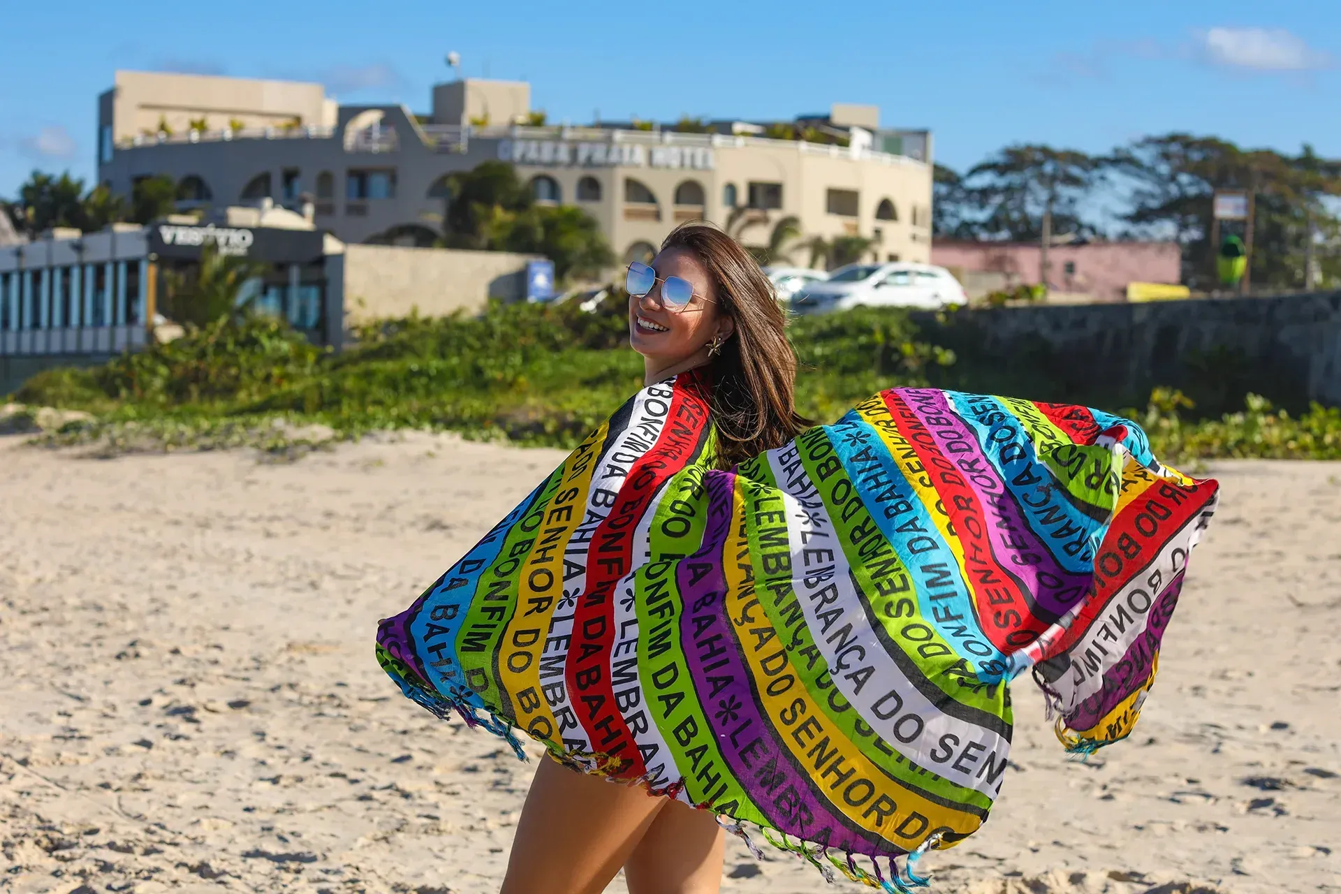 Uma mulher está na praia usando um lenço colorido.