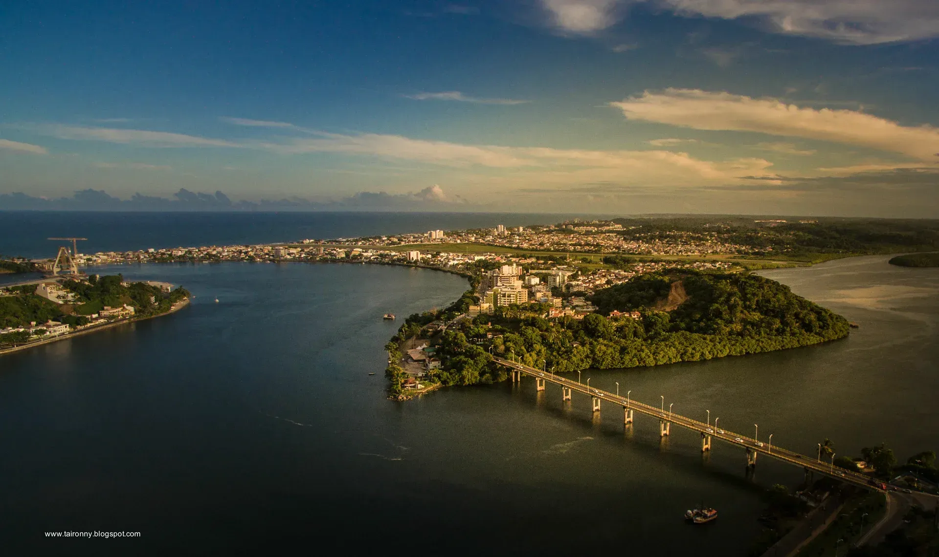 Uma vista aérea de uma ponte sobre um corpo de água com uma cidade ao fundo.