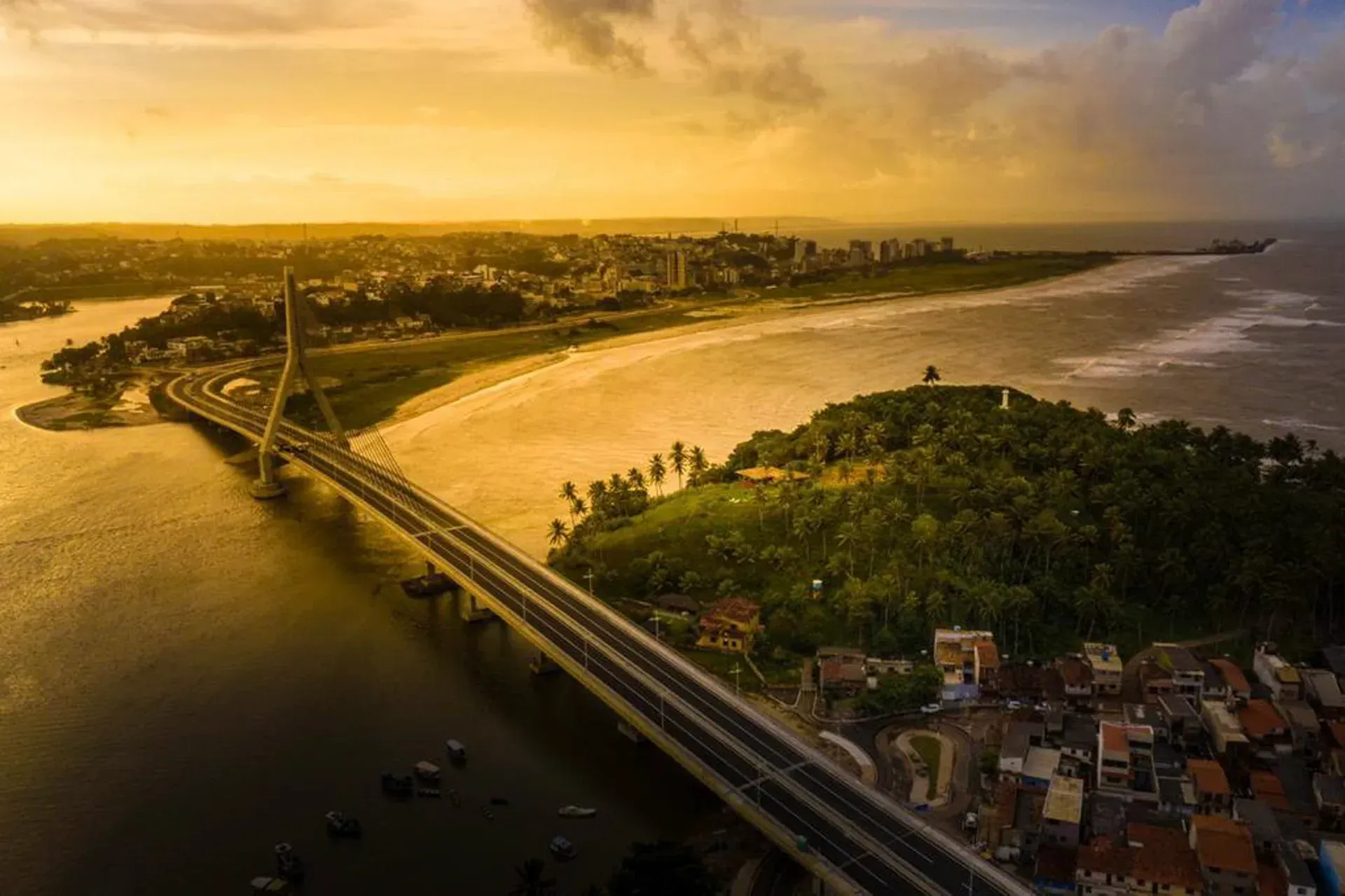 Uma vista aérea de uma ponte sobre um rio ao pôr do sol.