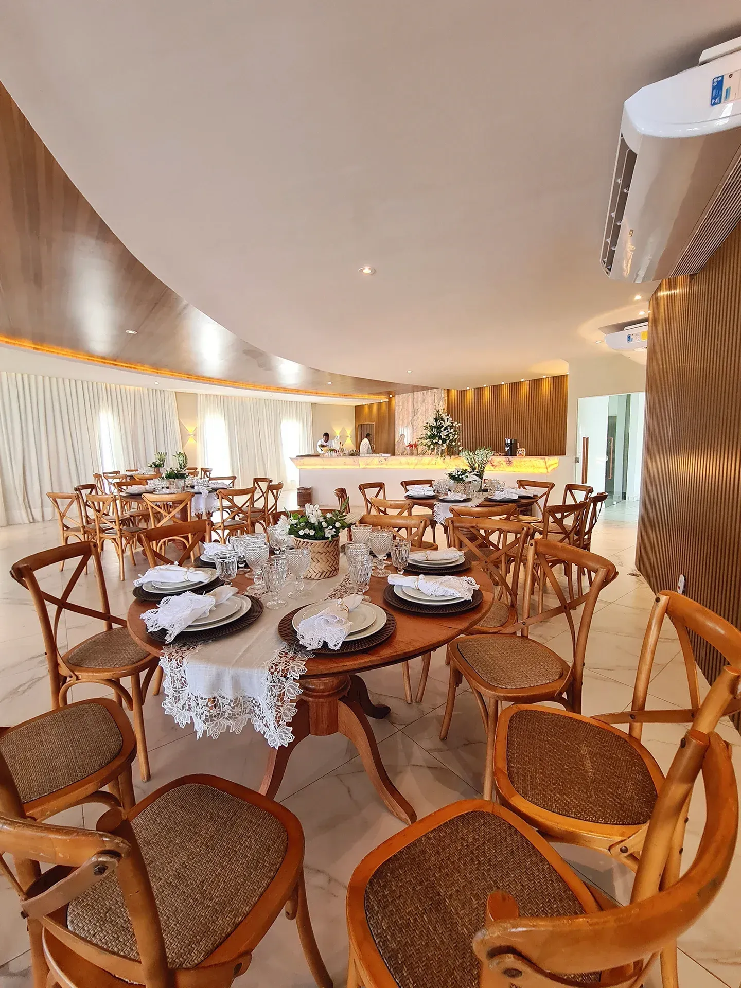 Uma grande sala de jantar com mesas e cadeiras e pratos.