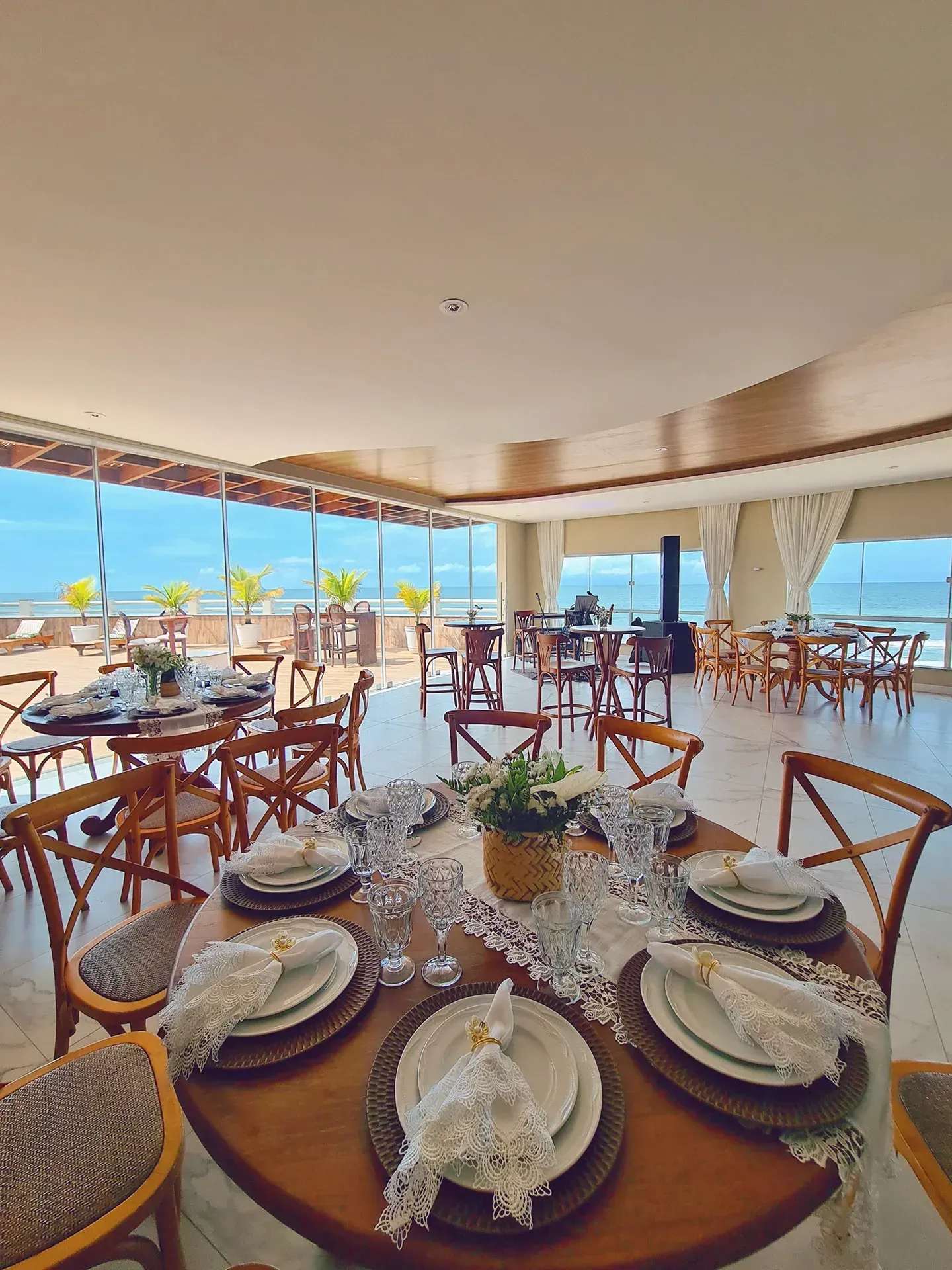 Uma grande sala de jantar com mesas e cadeiras e vista para o mar.