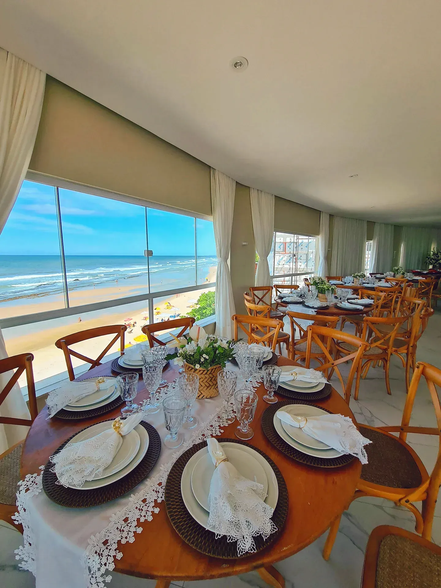 Uma sala de jantar com mesas e cadeiras e vista para o mar.