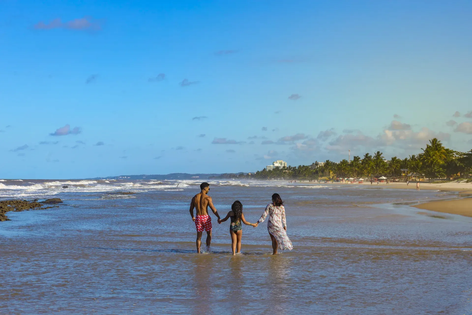 Uma família está andando na praia de mãos dadas.