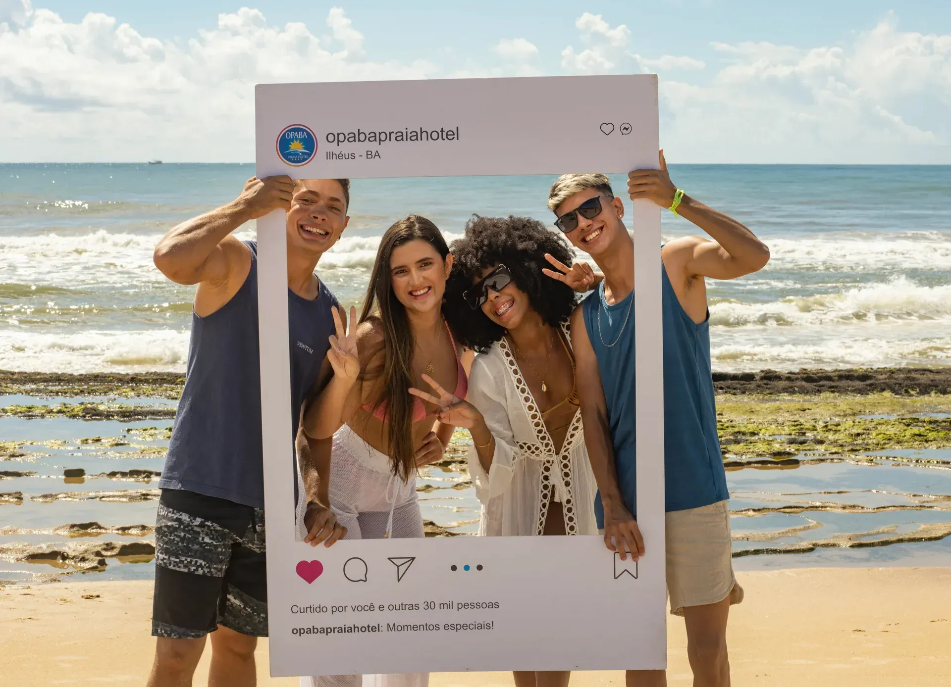 Um grupo de pessoas está em uma praia segurando um porta-retratos.