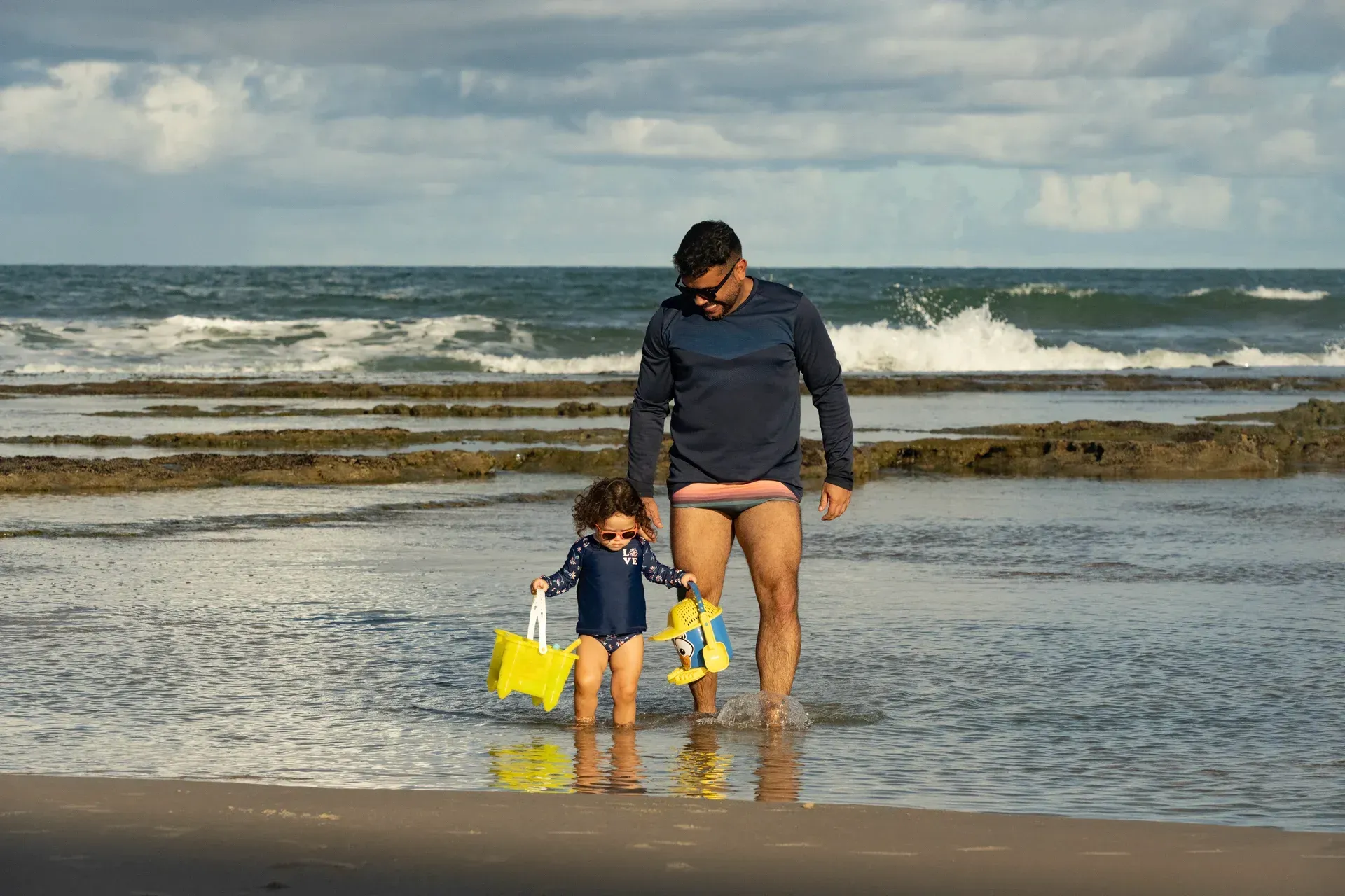 Um homem e uma menina estão caminhando na praia.