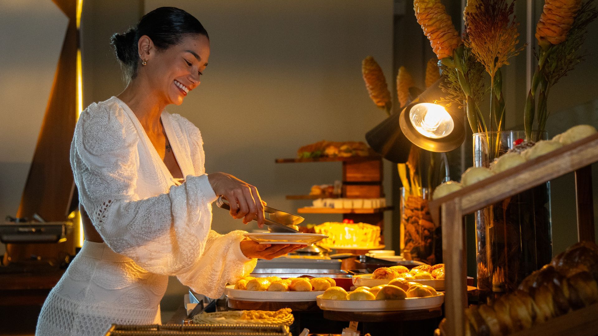 Uma mulher com um vestido colorido está segurando um prato de comida.