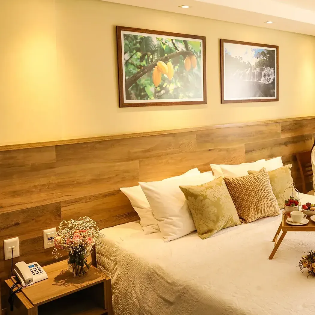 Um quarto com cama, mesa de cabeceira e dois quadros na parede.