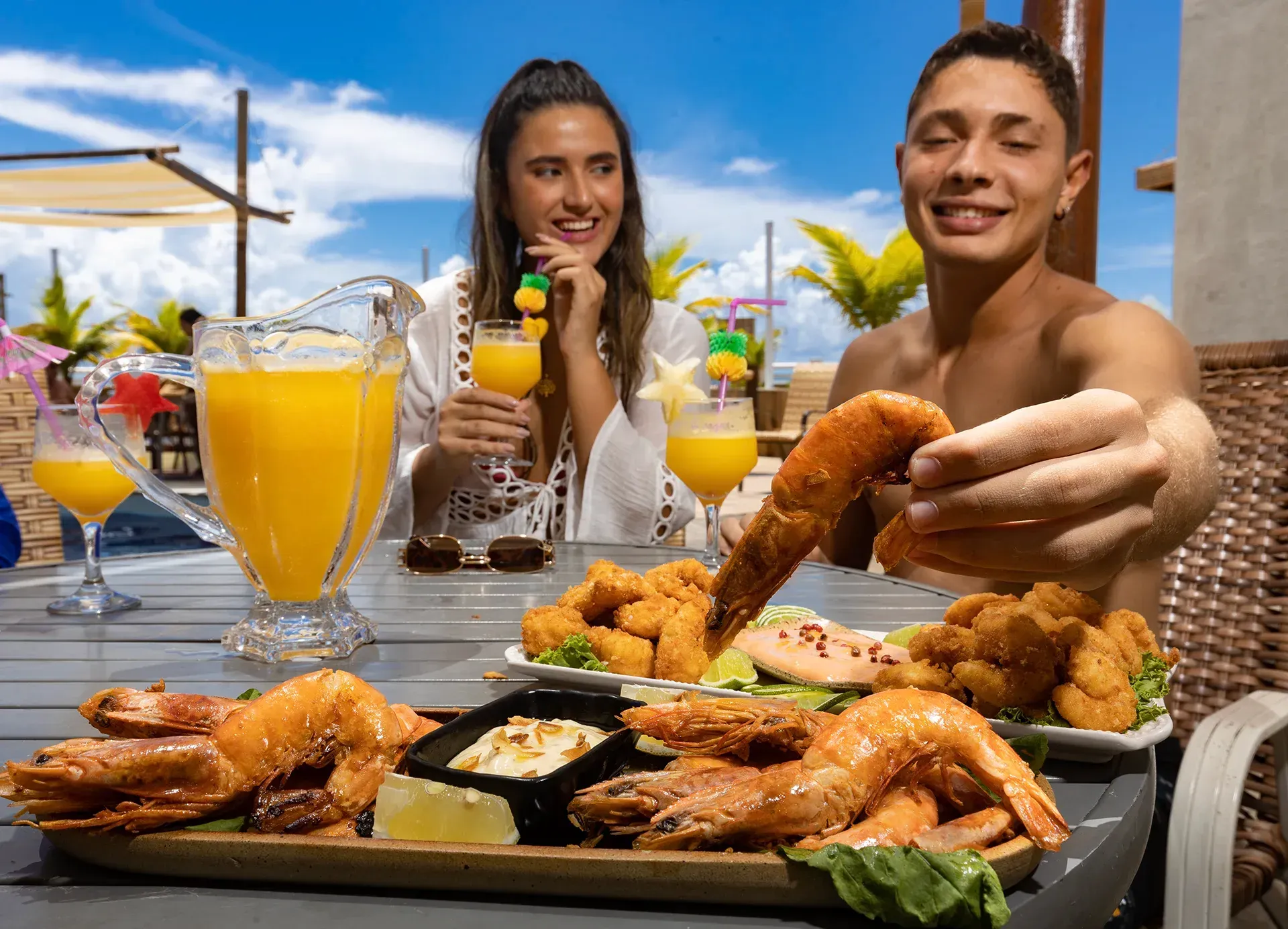 Um homem e uma mulher estão sentados à mesa comendo camarão.