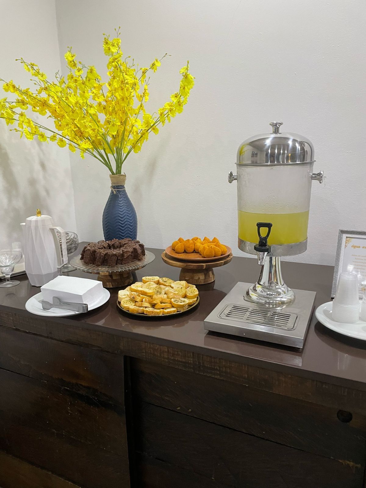 Uma mesa com pratos de comida e um dispensador de bebidas.