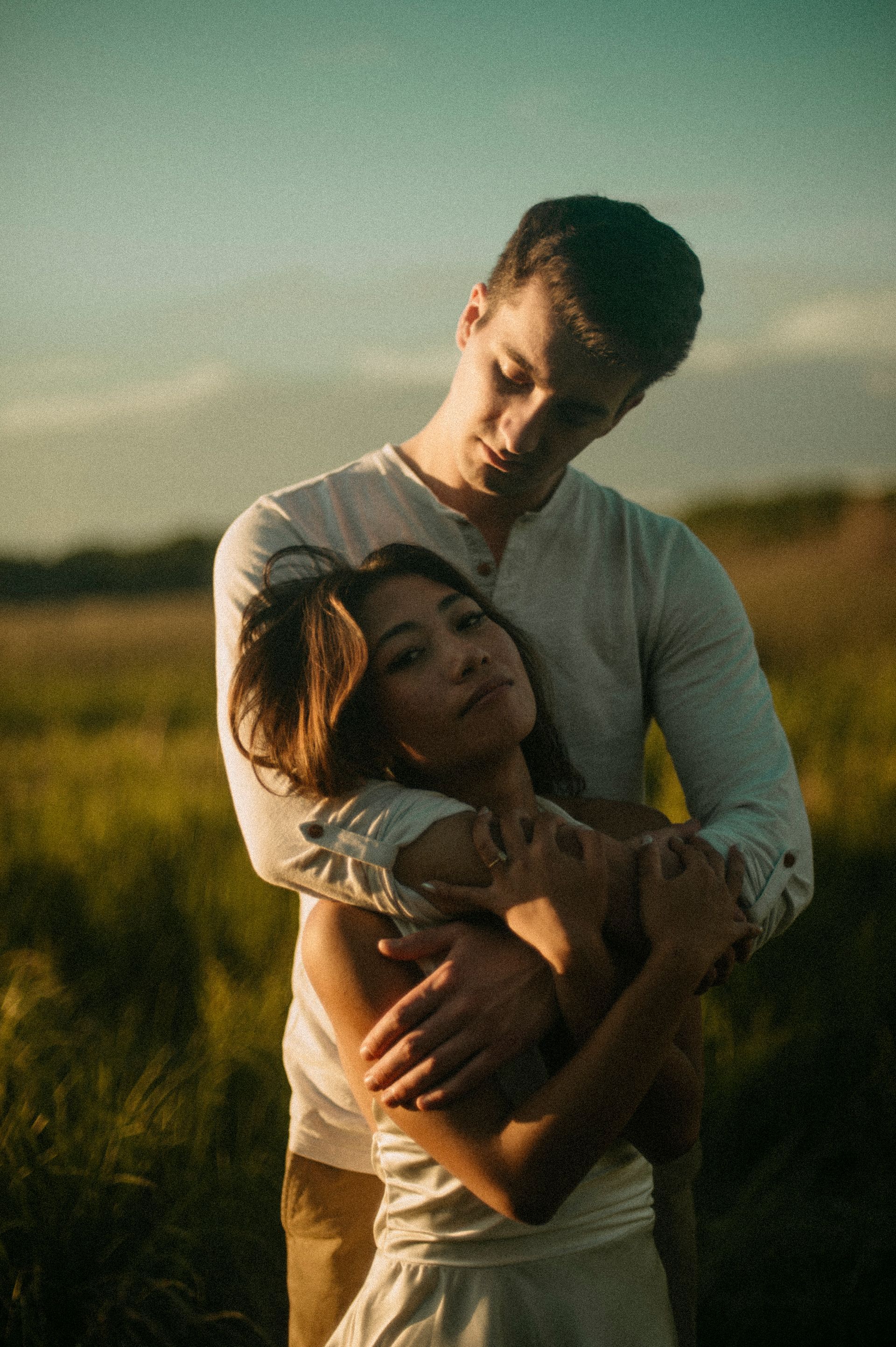 Man hugging woman in a field. Warm sunlight.