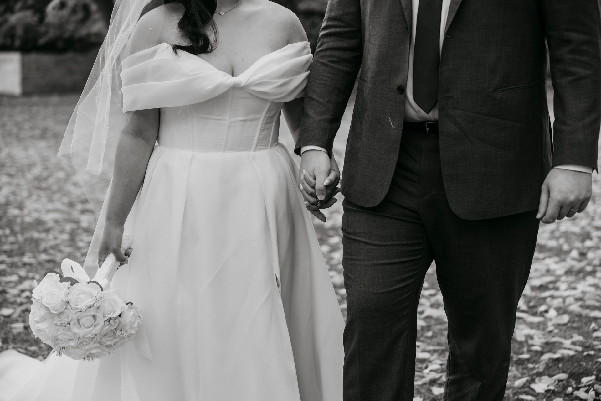 Bride and groom holding hands, bride in white dress and veil, groom in suit.
