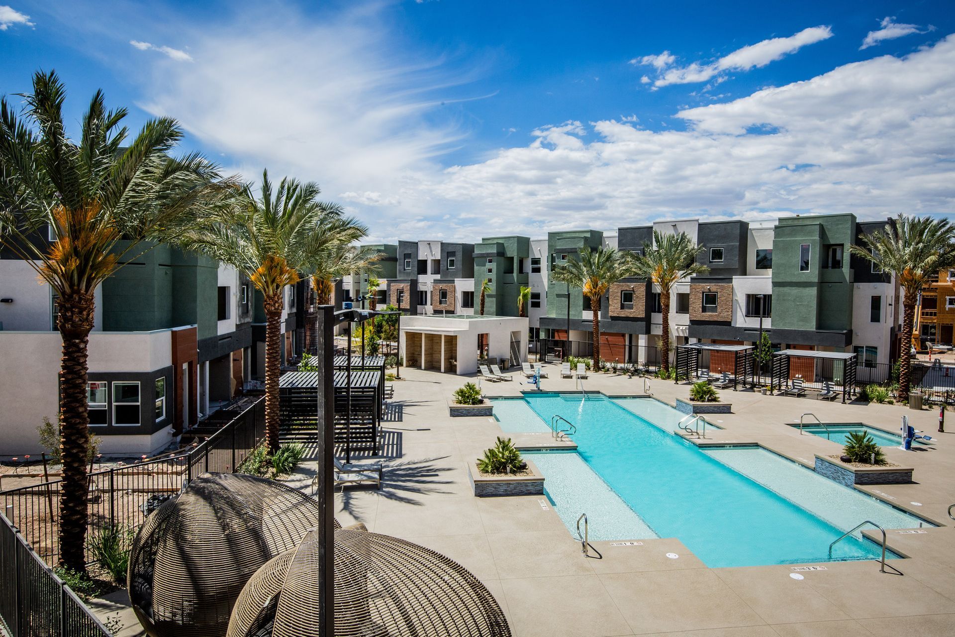 A large swimming pool in front of a building with palm trees