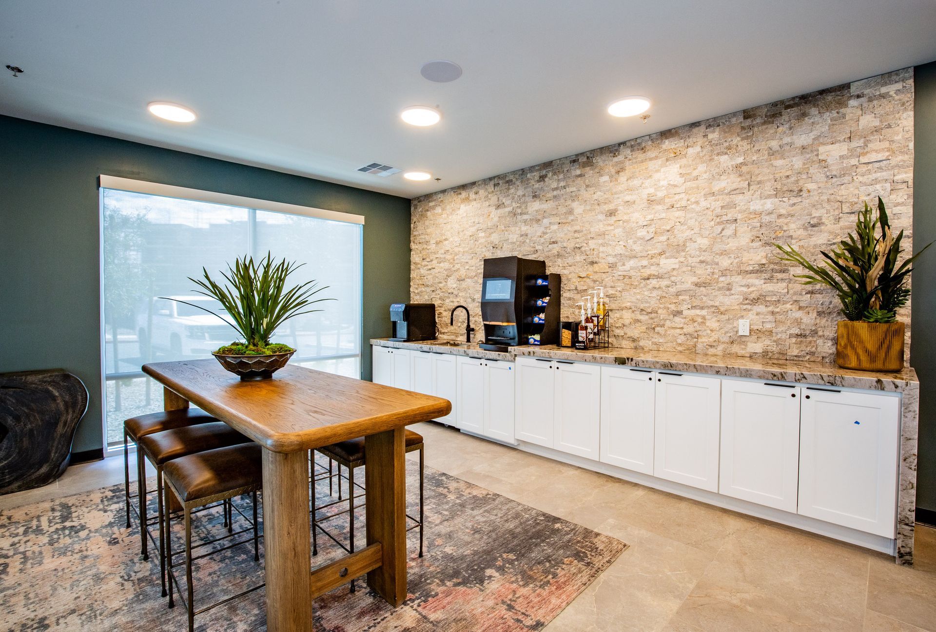 A kitchen with a wooden table and stools and a brick wall.