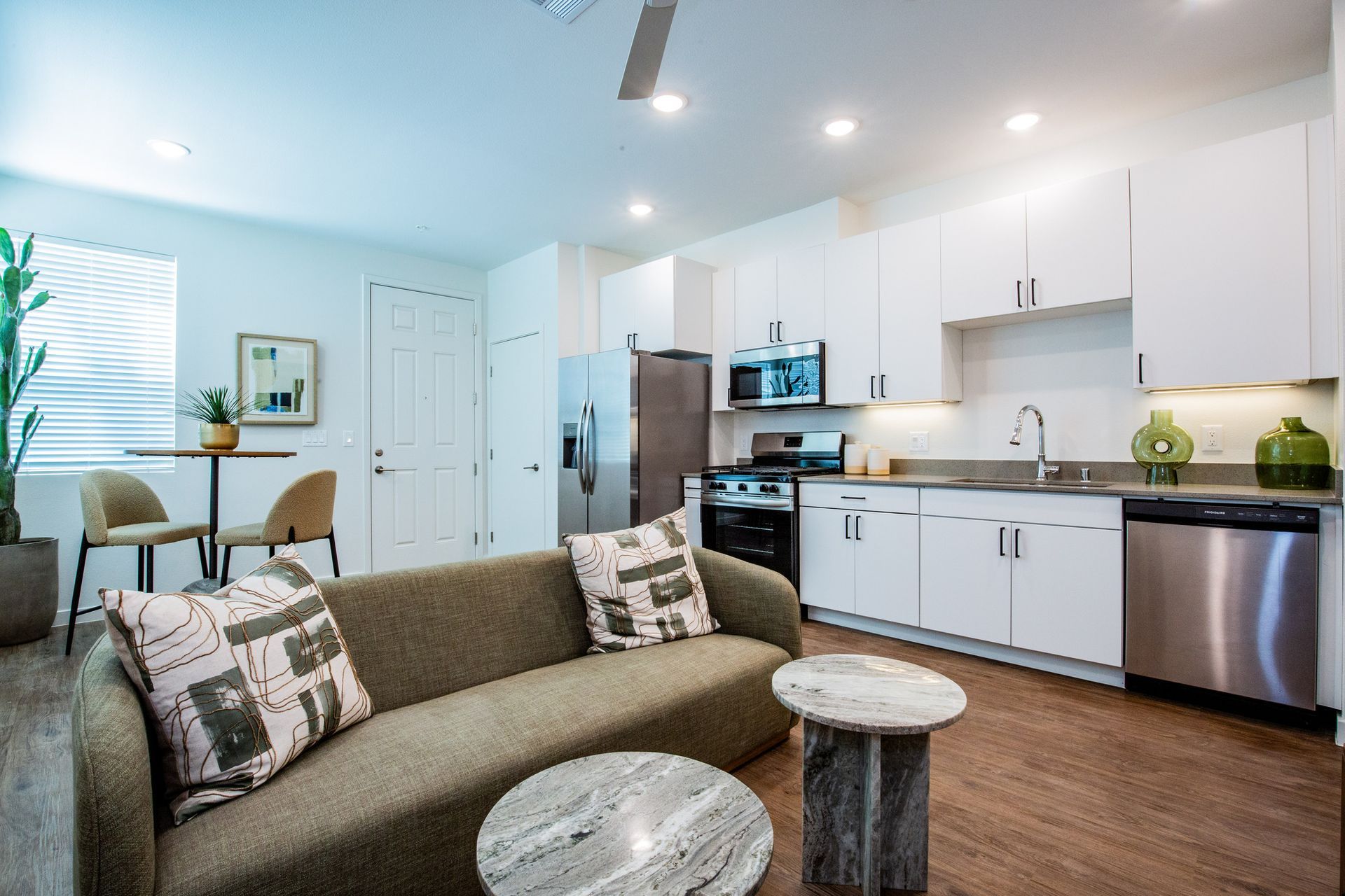 A living room with a couch and a kitchen with stainless steel appliances.