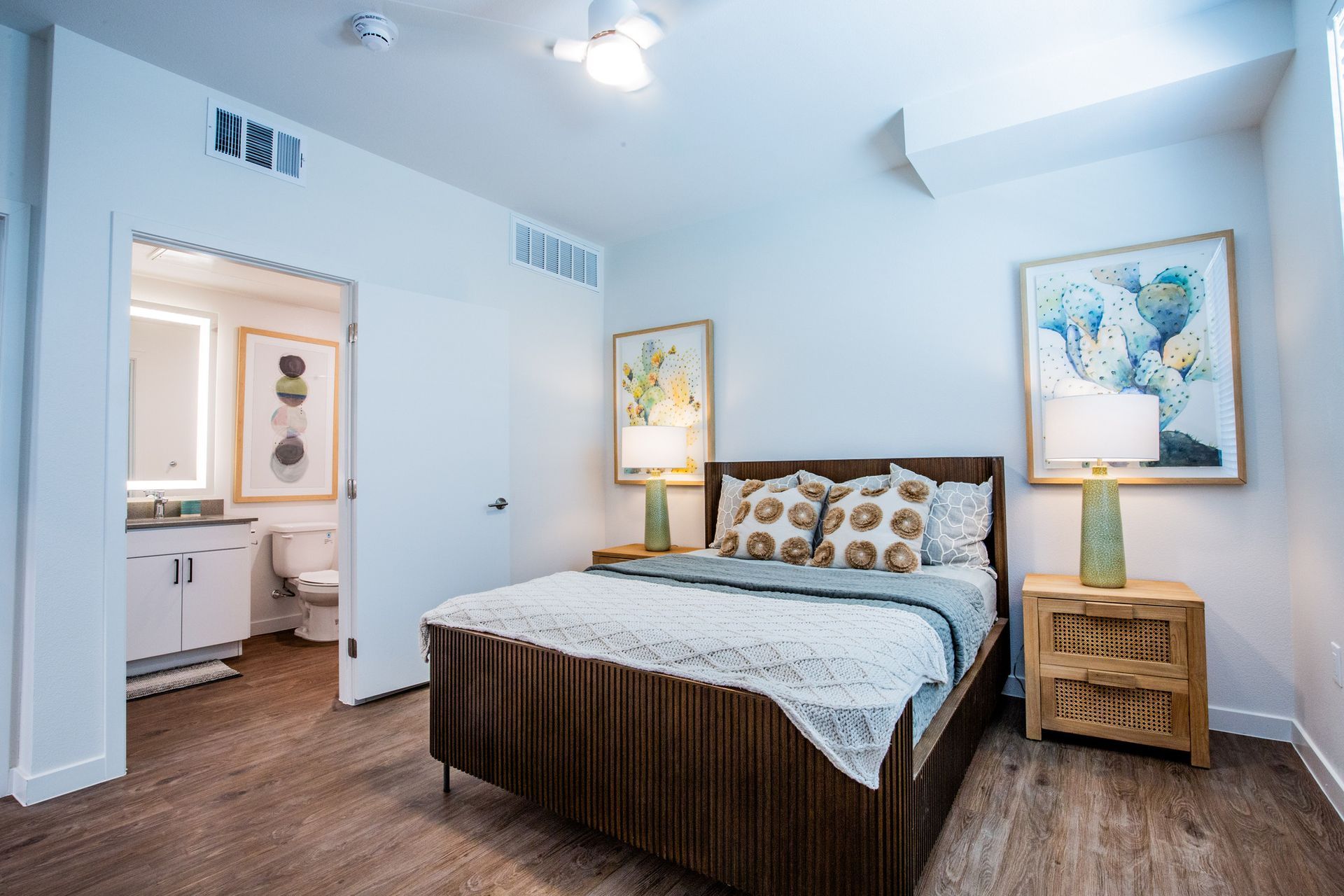 A bedroom with a large bed , nightstands , lamps and a bathroom.