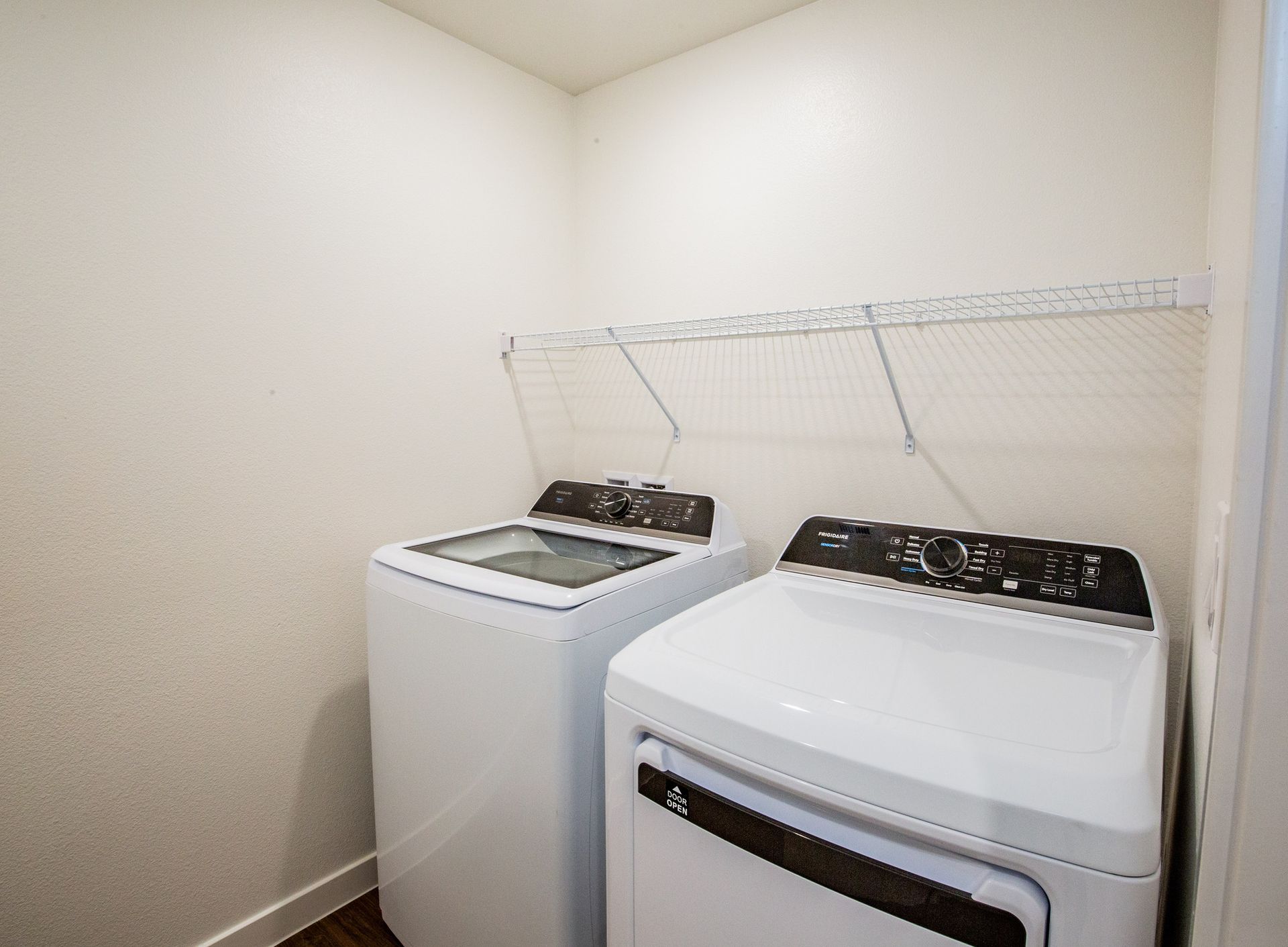 Two white washers and dryers are in a laundry room.