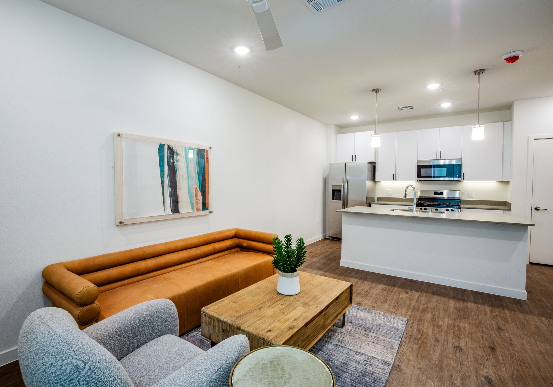 A living room with a couch , chair , coffee table and kitchen.