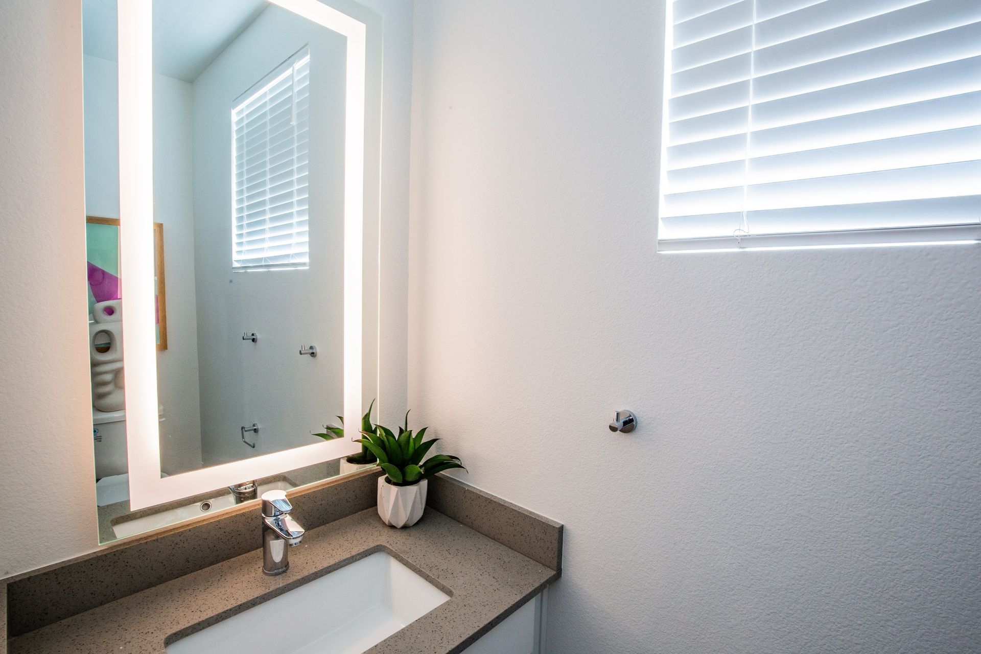 A bathroom with a sink , mirror and window.