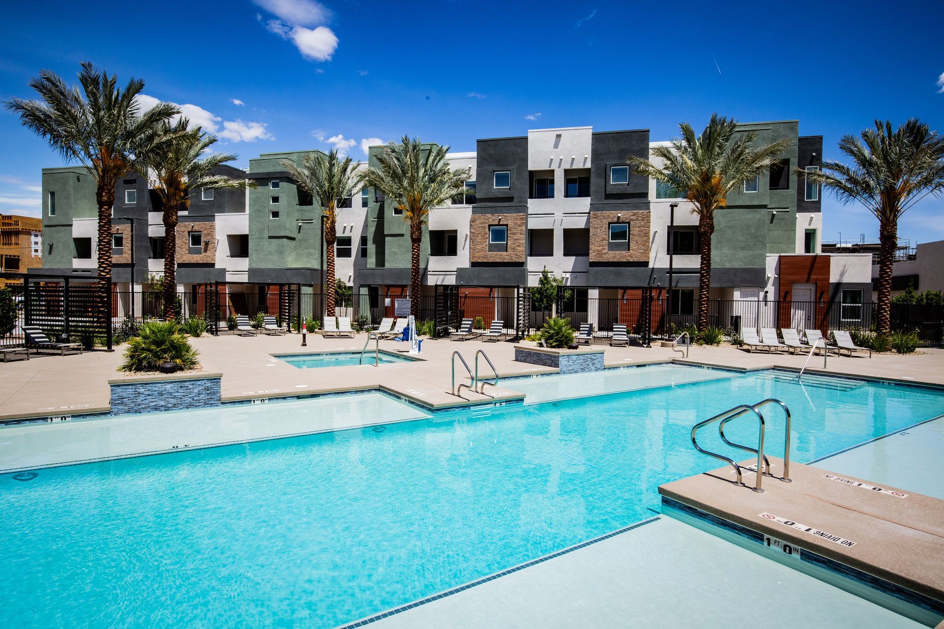 A large swimming pool in front of a building with palm trees
