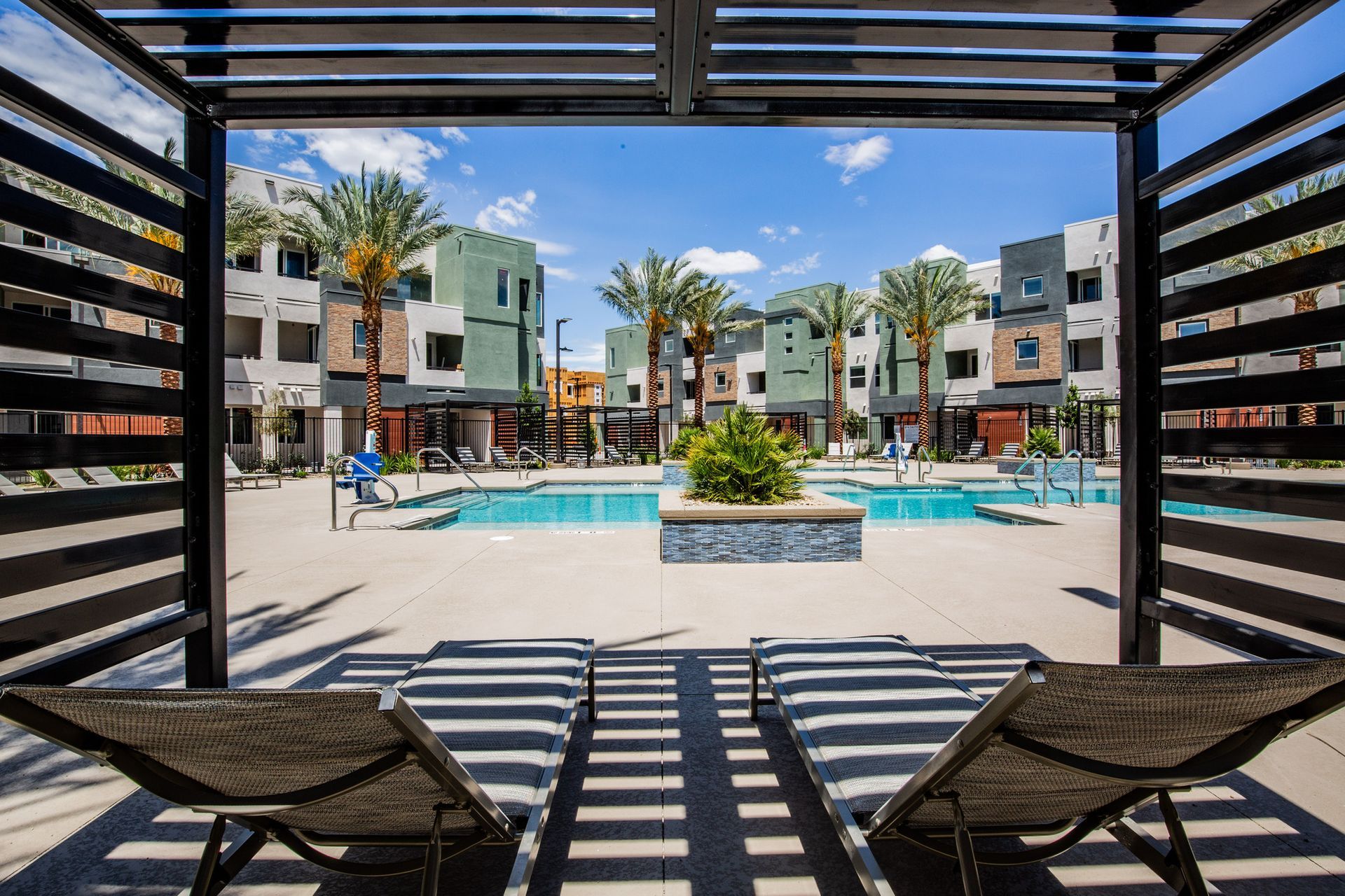There are two lounge chairs under a canopy overlooking a swimming pool.