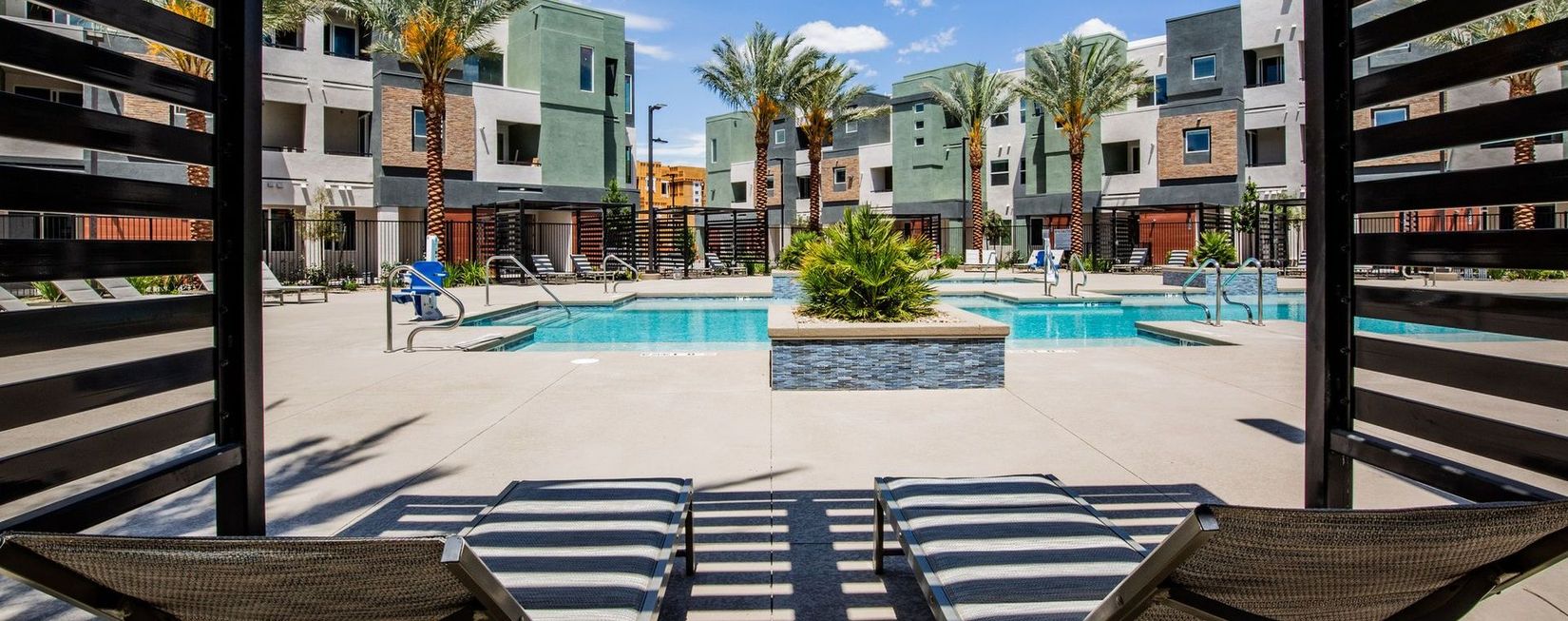 A large swimming pool surrounded by buildings and palm trees.