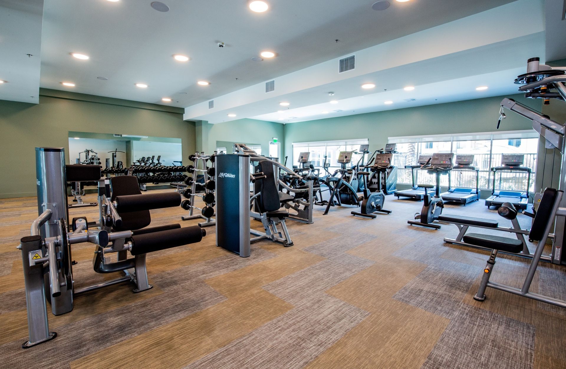 A large gym filled with lots of exercise equipment.