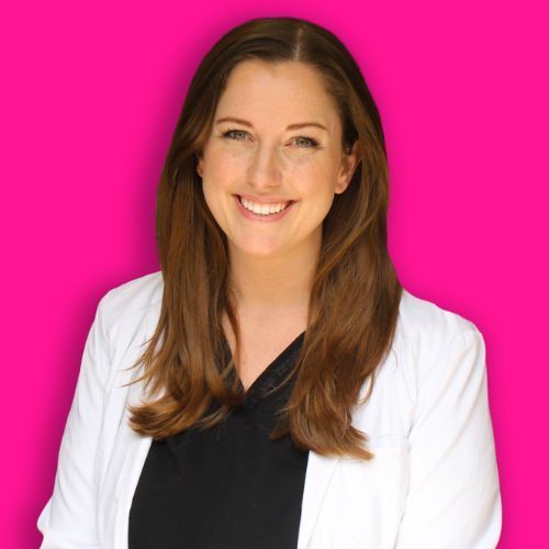 A smiling person with long brown hair, wearing a white lab coat over a black shirt, set against a bright pink background.