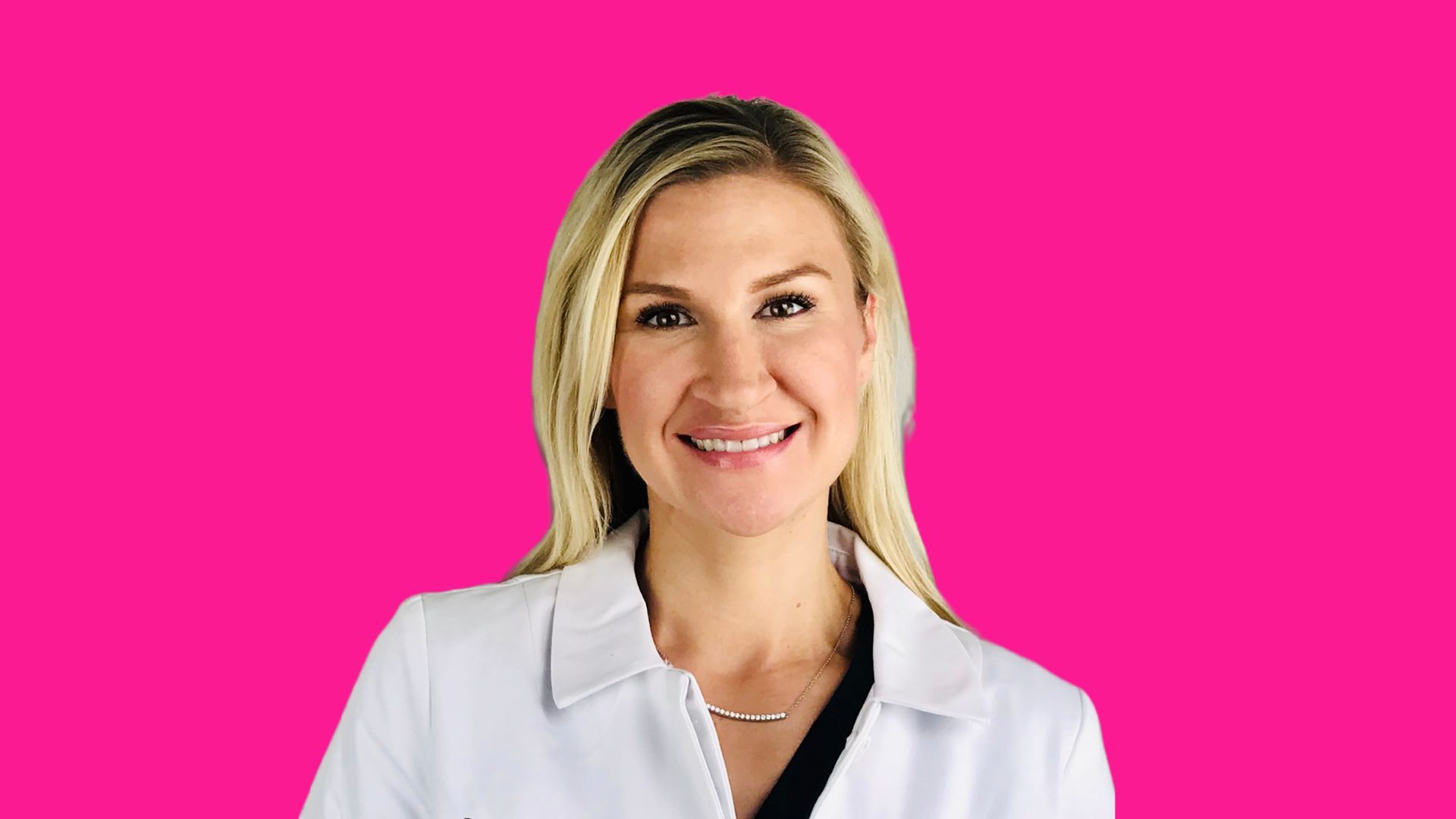 Smiling person with blonde hair wearing a white lab coat against a bright pink background.