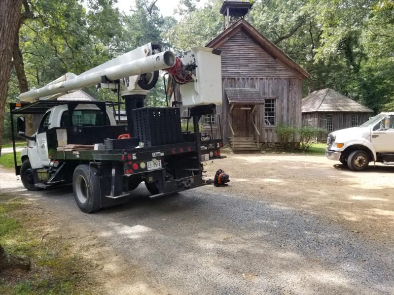 A truck with a crane on the back is parked in front of a wooden building.
