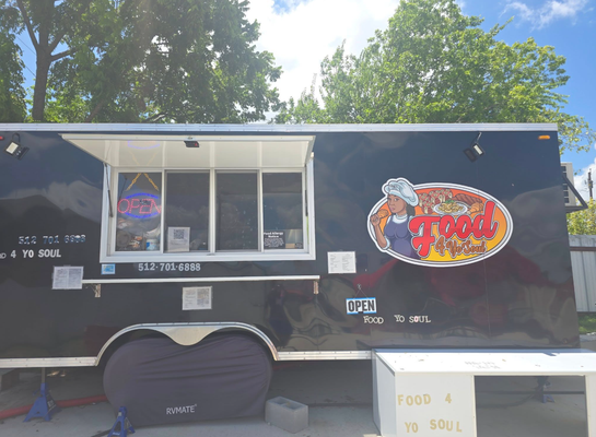 Black food truck with open serving window and logo of a chef; 