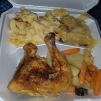 A takeout meal: roasted chicken leg, mac and cheese, cabbage, carrots, and potatoes in a styrofoam container.