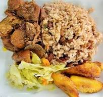 Plate of Jamaican food: chicken, rice and peas, cabbage, and fried plantains.